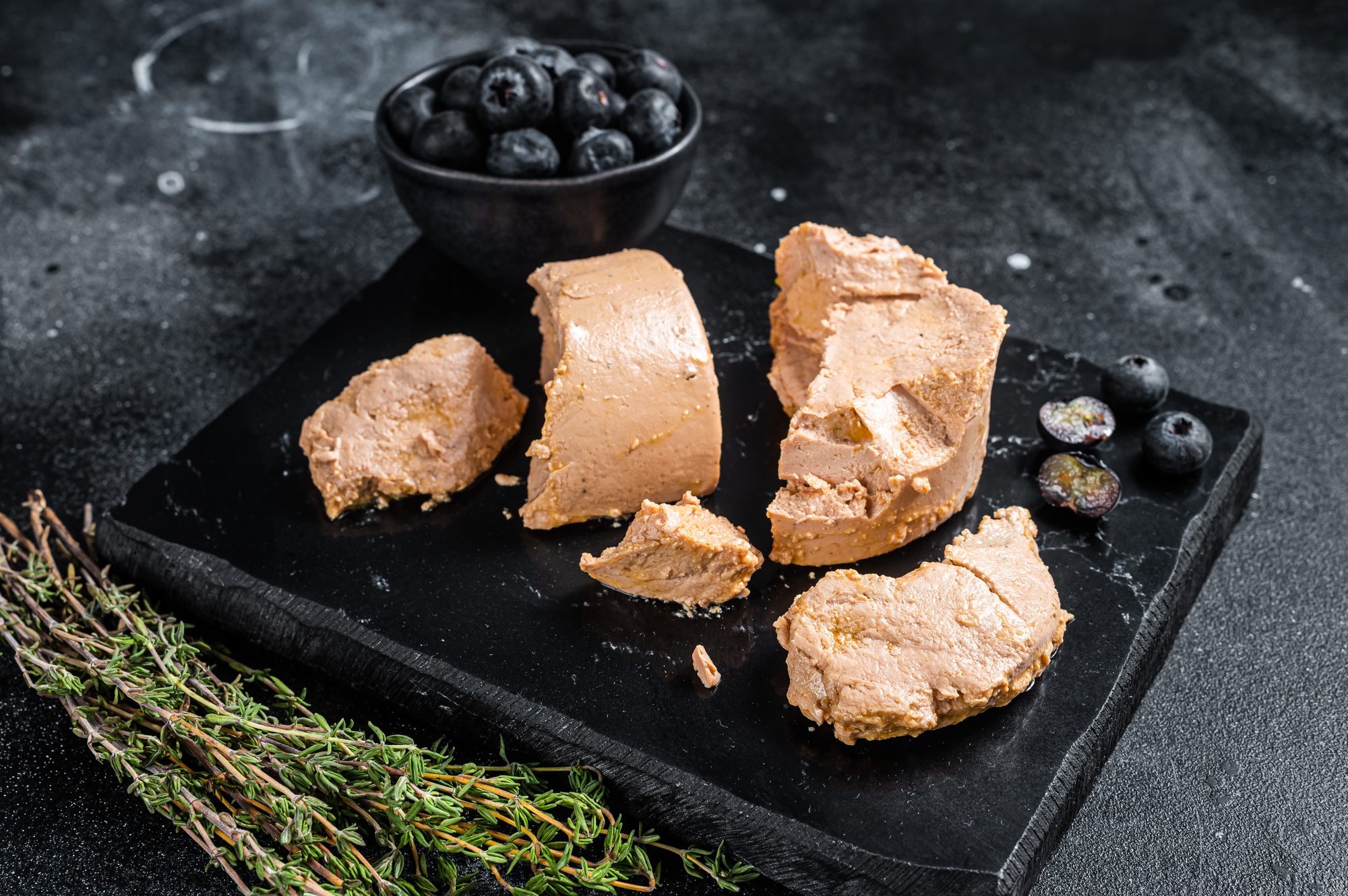Foie gras duck liver pate and fresh blueberry. Black background. Top view