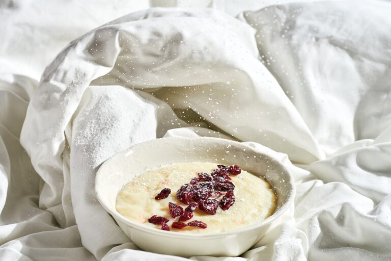 Semolina porridge with berries in a plate on a white sheet. Hard light.