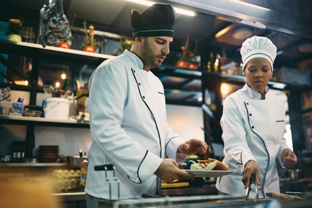Two chefs cooperating while preparing meal in a restaurant.