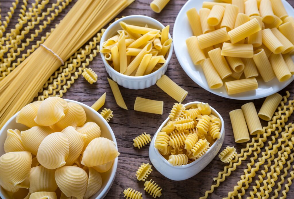 Various types of pasta on the wooden background