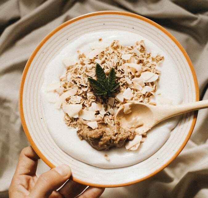 a person holding a plate of food on a bed
